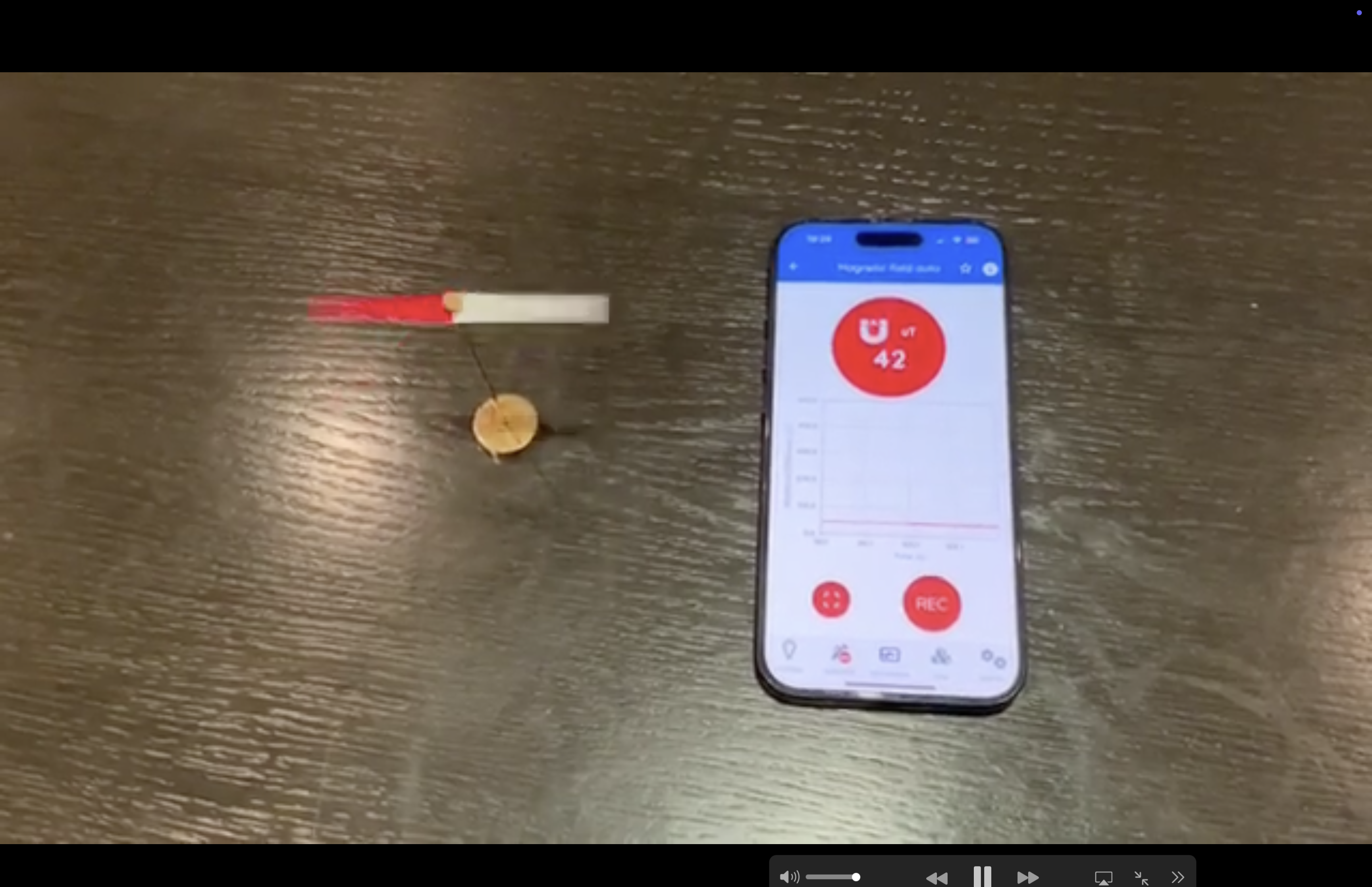 Aimant droit posé près d'un smartphone affichant la mesure du champ magnétique